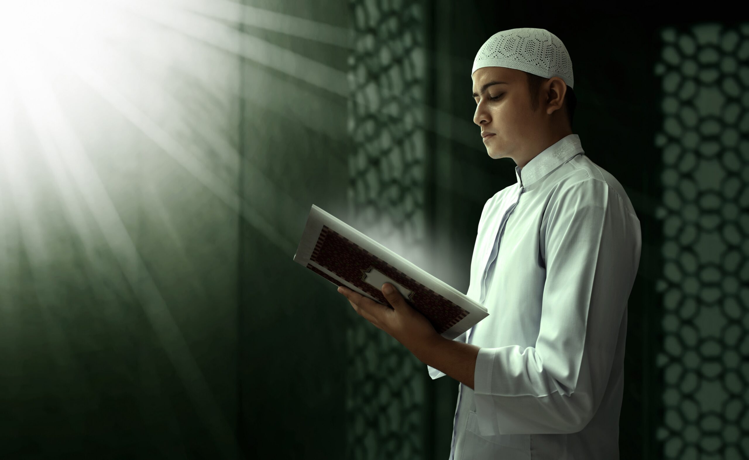 Young man reading the Quran near a window